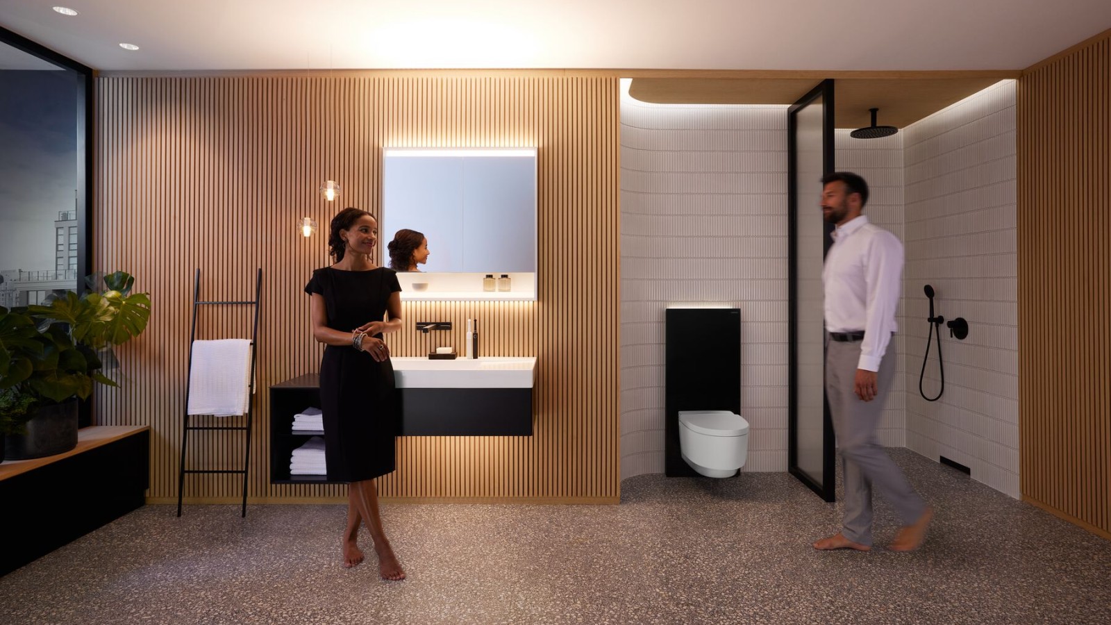 Hombre y mujer en un baño perfectamente iluminado con productos Geberit ONE Hombre y mujer en un baño perfectamente iluminado con productos Geberit ONE