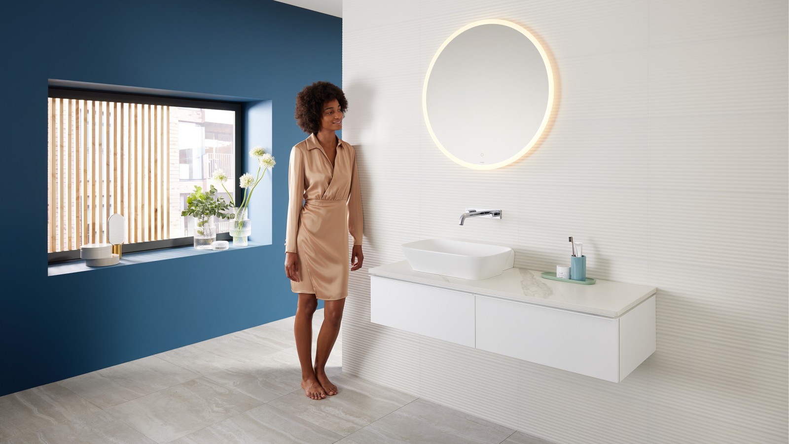 Mujer apoyada en la pared del baño con productos de la gama Geberit Mix & Match Mujer apoyada en la pared del baño con productos de la gama Geberit Mix & Match