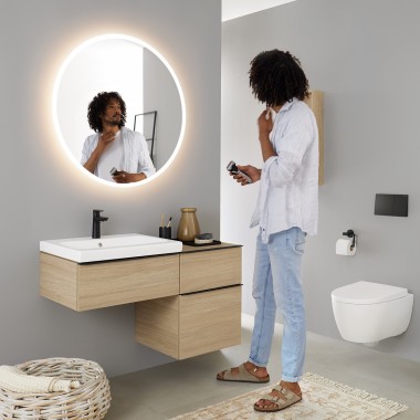 Hombre mirándose en un espejo redondo con luz Geberit Option Hombre mirándose en un espejo redondo con luz Geberit Option