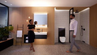 Hombre y mujer en un baño perfectamente iluminado con muebles de baño y sanitarios Geberit ONE (© Geberit)