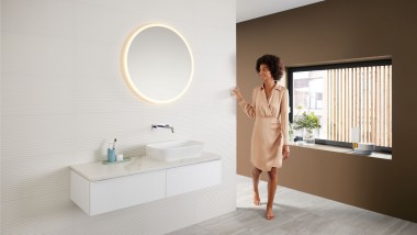 Mujer en un baño moderno con una paleta de colores marrones — la última tendencia en color para baños — y una combinación de lavabo Mix & Match.