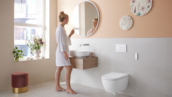 Mujer en baño con Geberit AquaClean Alba: un inodoro bidé económico