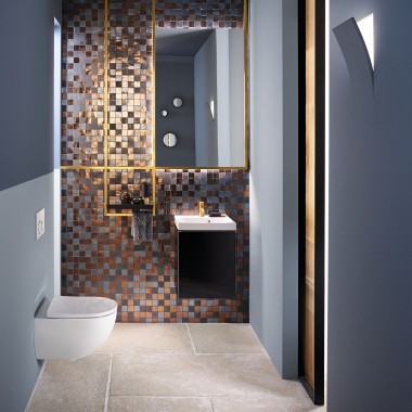 Vista de un baño de invitados moderno con un inodoro y un lavabo Acanto frente a una pared con mosaico