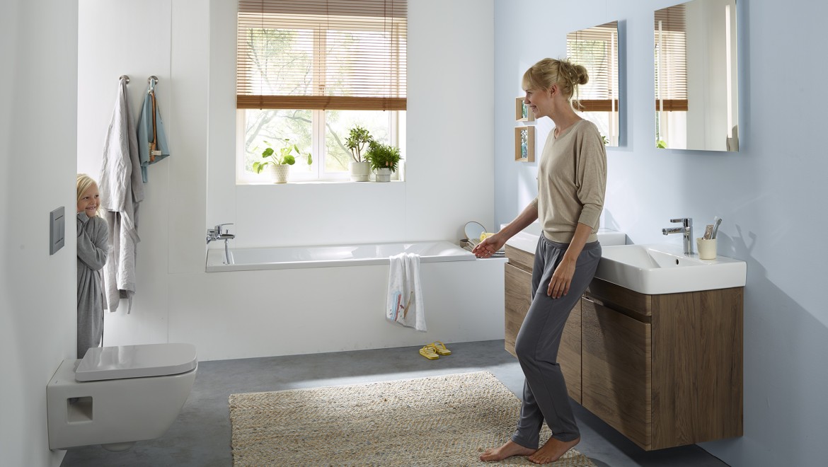 Mujer y niño de pie en un baño familiar de la serie Geberit Selnova (© Geberit)