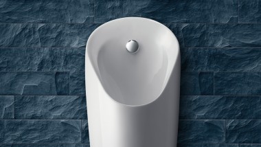 Urinario Preda instalado en una pared gris (© Geberit)