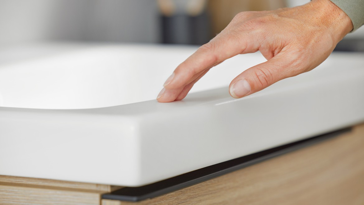 Imagen macro de una mano tocando un lavabo Geberit iCon en blanco mate Imagen macro de una mano tocando un lavabo Geberit iCon en blanco mate