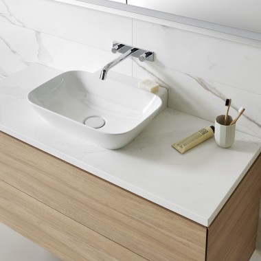 Lavabo con sanitarios blancos y muebles de baño de madera (© Geberit)