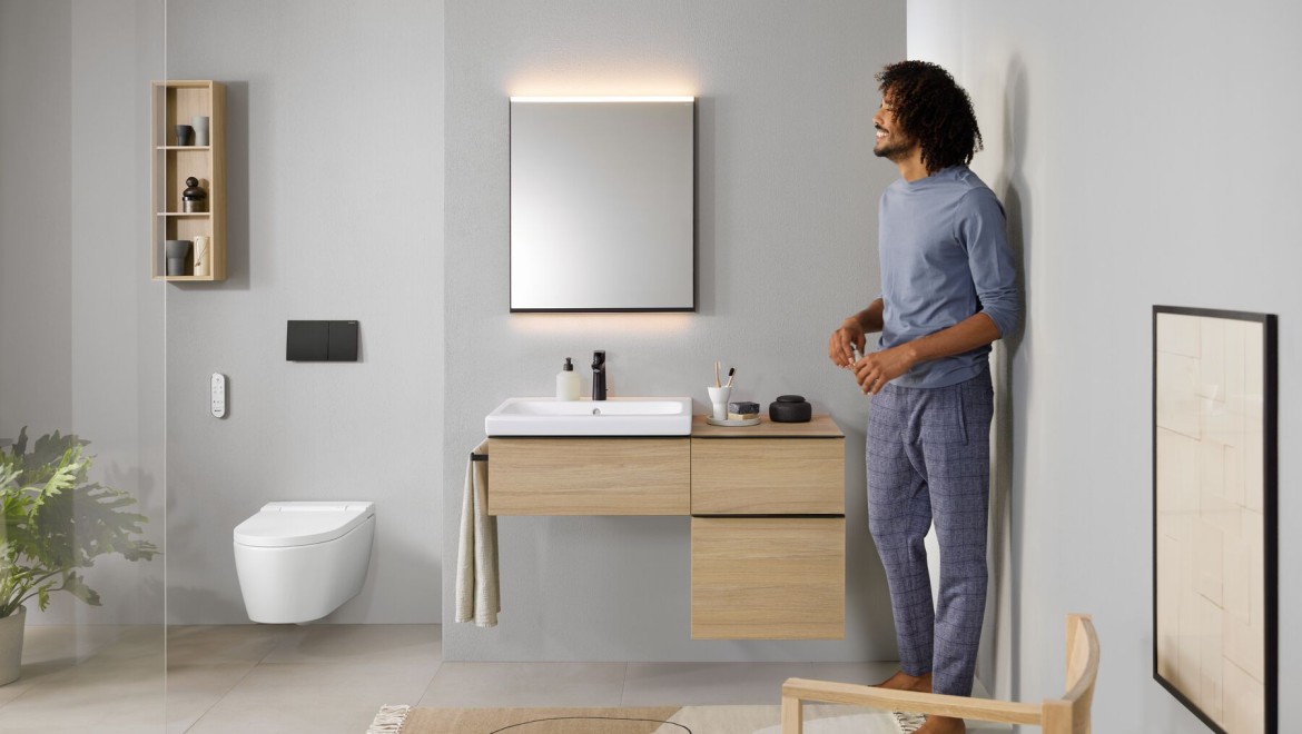 Hombre de pie en el baño con un inodoro bidé AquaClean Sela Hombre de pie en el baño con un inodoro bidé AquaClean Sela