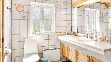 Baño original con inodoro al suelo, azulejos blancos y muebles de baño de madera (© @triner2 y @strandparken3)