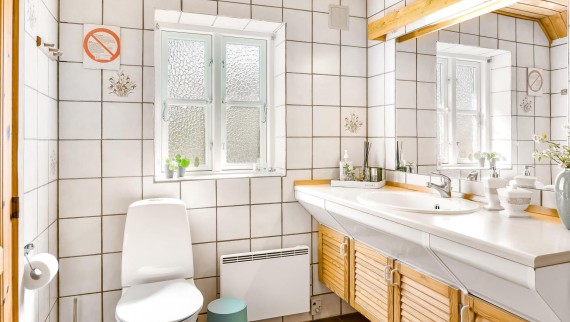 Baño original con inodoro al suelo, azulejos blancos y muebles de baño de madera (© @triner2 y @strandparken3)