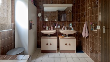 Cuarto de baño con azulejos marrones y dos lavabos