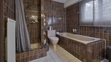 Cuarto de baño con espacio de ducha estrecho, bañera y WC al suelo