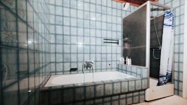 Cuarto de baño con azulejos azules, cabina de ducha y bañera
