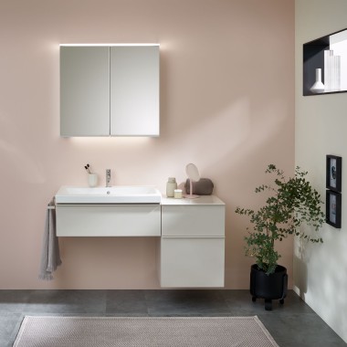 Lavabo con mueble del baño, lavabo y armario con espejo de Geberit delante de una pared pastel Lavabo con mueble del baño, lavabo y armario con espejo de Geberit delante de una pared pastel