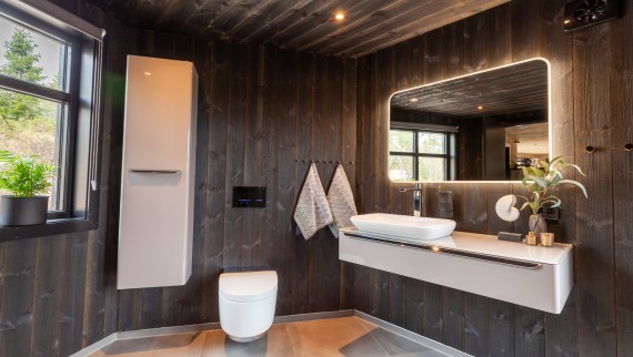 El baño también está revestido de madera y, además del inodoro bidé AquaClean Mera, hay otros productos Geberit instalados en él (© Geberit)