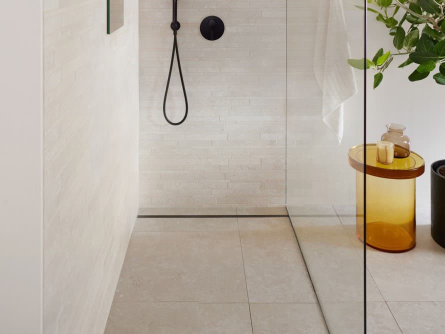 Baño con azulejos grandes y ducha a ras de suelo.